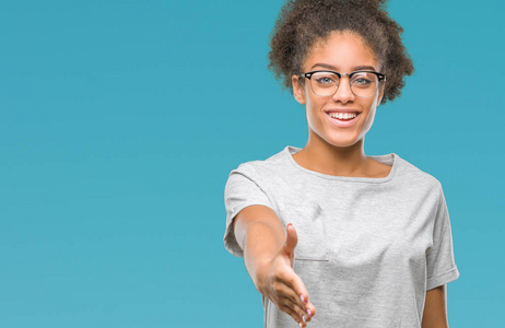 年轻的美国黑人妇女戴眼镜在孤立的背景微笑友好提供握手作为问候和欢迎。成功的企业