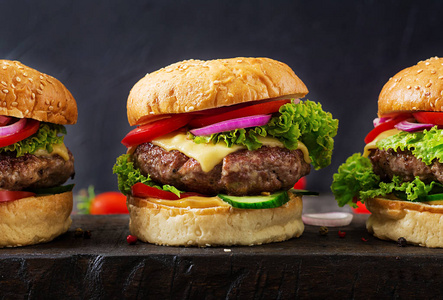 汉堡包与牛肉肉汉堡和新鲜蔬菜在黑暗的背景。美味