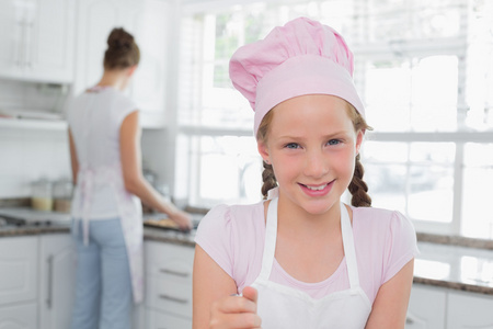 一个年轻的姑娘戴厨师的帽子在厨房里的特写镜头