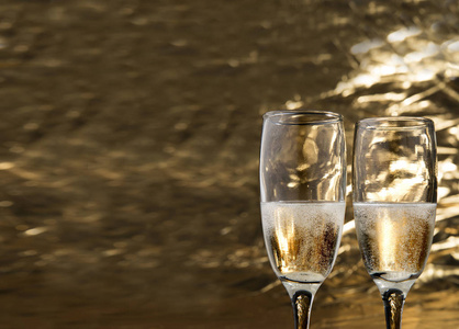 一对白色的葡萄酒玻璃与金色的背景。派对和庆祝理念