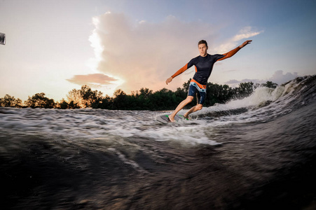 在湖滨背景下, wakeboarder 的主动雄马骑在摩托艇上的冲浪板上