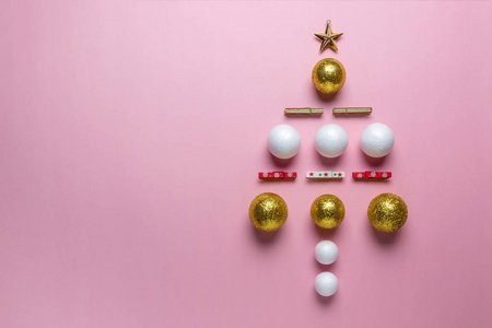 圣诞树由金色, 白色和红色闪闪发光的球装饰在粉红色的背景。新年最小的概念。扁平