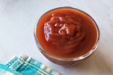 在玻璃碗里放番茄酱。快餐调味汁