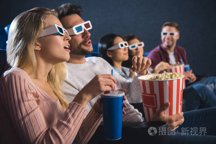 多民族朋友在3d眼镜与爆米花一起看电影在电影院