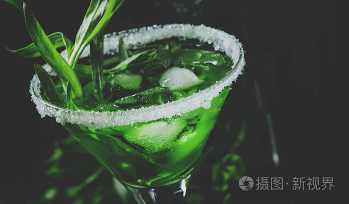 绿色万圣节鸡尾酒与龙嵩和冰在马提尼玻璃黑暗背景与振动筛