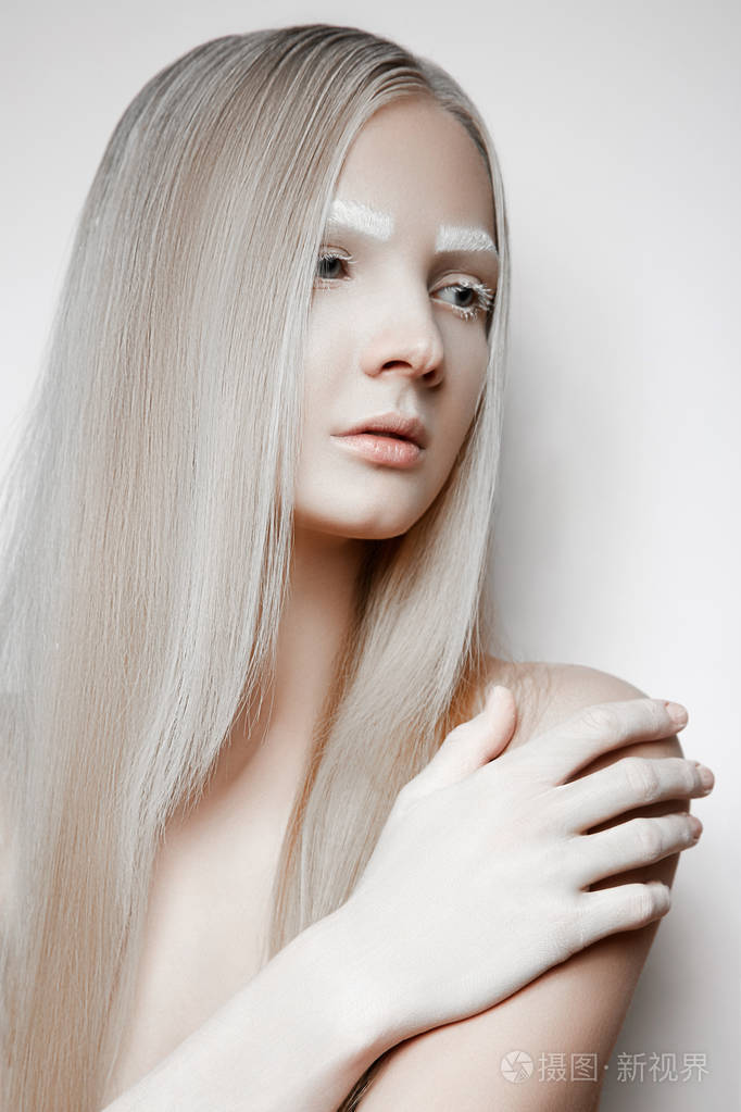 美丽的金发碧眼的女孩与白色的眉毛看着她的手在肩膀上的一侧