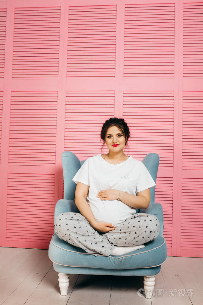 快乐美丽的孕妇坐在椅子上在家