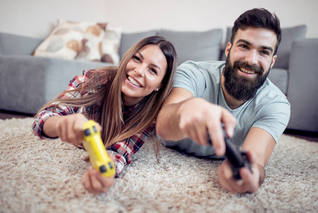 年轻夫妇玩电子游戏。他们在一起微笑和欢笑