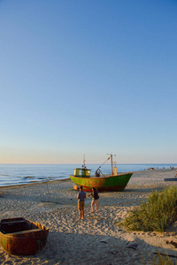 日出时间在夏天的海滩上的渔夫船