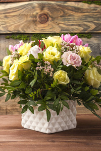 华丽的花束, 多色玫瑰和其他花卉在一个白色的花瓶, 在一个木质的背景