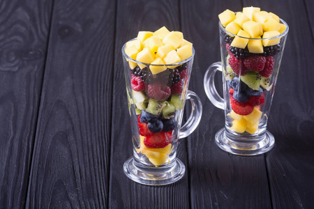 新鲜水果和浆果沙拉在玻璃。健康维他命食品背景