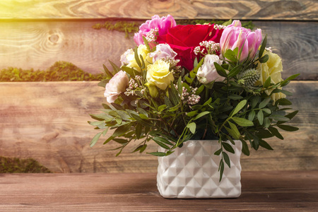 华丽的花束, 多色玫瑰和其他花卉在一个白色的花瓶, 在一个木质的背景