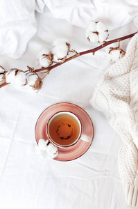 一杯热茶, 细棉枝和针织格子毛衣在床上与白色亚麻布。舒适的早餐在家里生活方式温和的女性背景复制空间秋天冬天的概念
