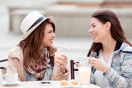 两个美丽的女人交谈, 喝咖啡, 柠檬水和坐在咖啡馆