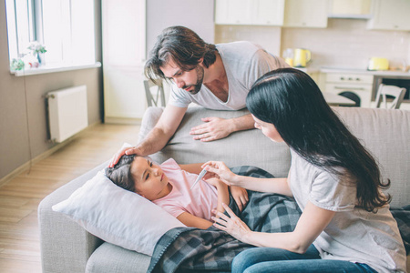 细心的父母正在看他们的孩子.他们碰她女孩在看着他们.她病了.