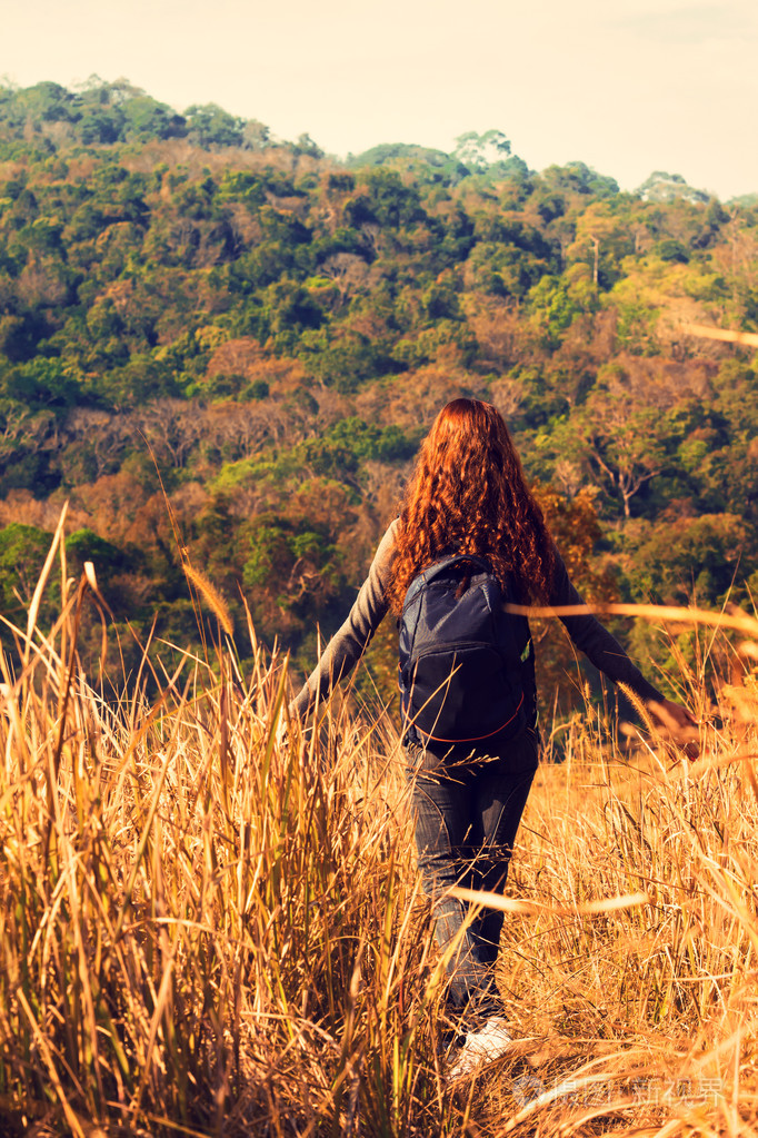 美丽的旅行者的女孩背着享受金色的麦田
