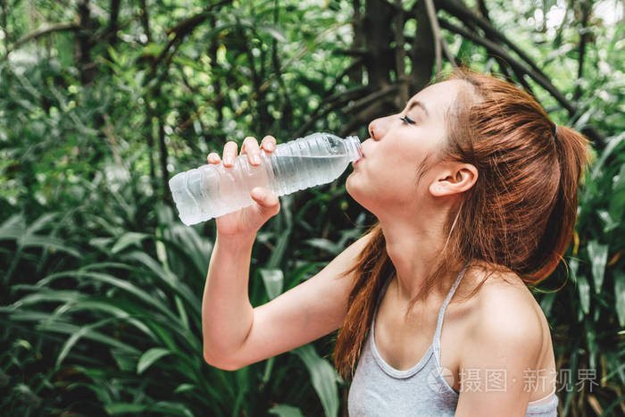 美丽的女人在绿色自然清新的空气中饮水。健康的生活方式概念