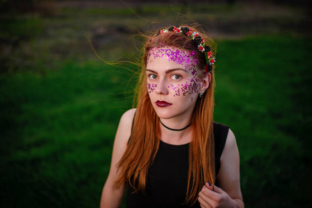一个年轻漂亮的女人, 她的脸上有紫罗兰色的光泽, 站在草地上看着相机