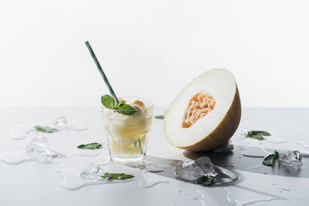 美味的夏日饮料, 薄荷和瓜在玻璃, 融化的冰块和半熟瓜白色