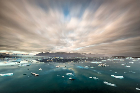 冰浮冰和冰山漂浮在 jokulsarlon 的泻湖上, 云卷在上面的天空