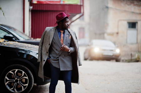 时尚的非洲裔美国人男子模型灰色大衣, 夹克领带和红帽反对黑色 suv 汽车