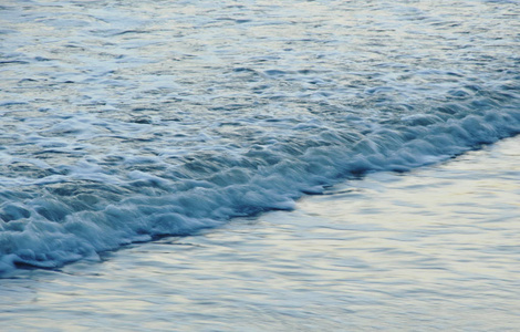 日落时海水在海滩上的海浪模糊