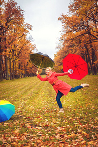 秋天公园里带着雨伞的快乐金发女郎