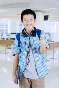 一个英俊的青春期学生的形象指向和眨眼在相机, 而站在学校
