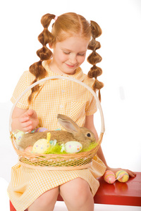 小女孩用一只篮子复活节彩蛋的兔子
