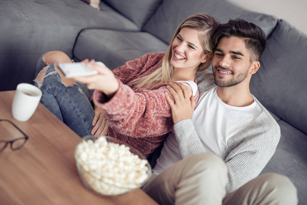 年轻夫妇在他们的公寓放松, 看电影和吃爆米花