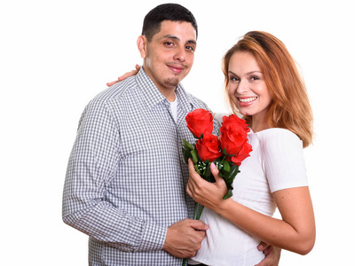 年轻愉快的拉美裔夫妇微笑和在爱捧红玫瑰