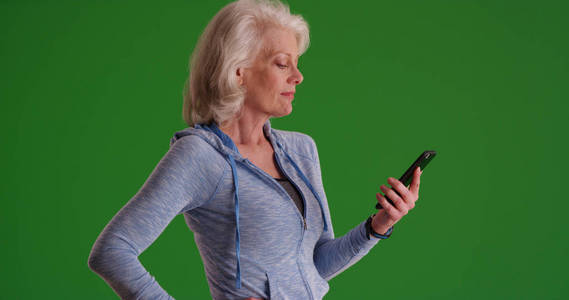 成熟的白种人妇女在智能手机上发短信在绿色屏幕上