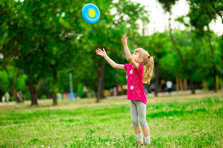 小女孩在运动中玩飞行盘, 在夏季公园玩休闲活动游戏