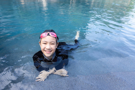 享受水的小女孩在游泳池里放松的女孩的画像, 穿泳装的小女孩享受水