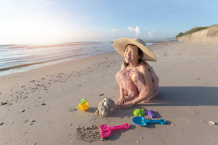 亚洲可爱的女孩在沙滩上玩沙子, 暑假和放松的概念