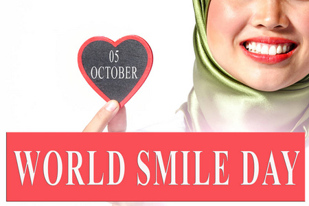 国际活动日历概念 世界微笑日, 10月5日以微笑的女性举行心脏形状工作室画像的背景在白色背景查出