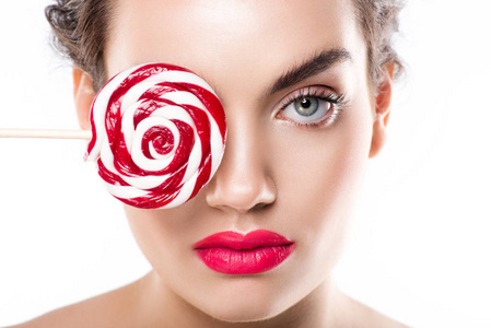 有吸引力的年轻妇女拿着红色棒糖在眼睛前面, 被隔绝在白色图片