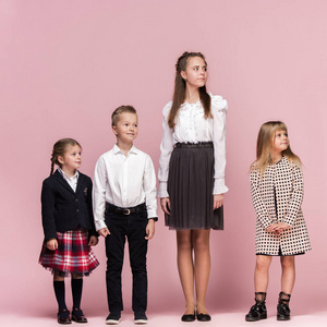 可爱时尚的孩子在粉红色工作室背景。美丽的少女和男孩站在一起