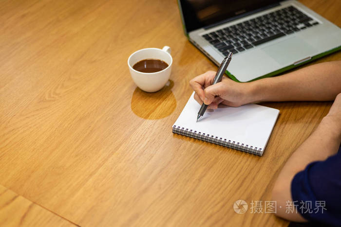 女人手拿钢笔开始写空白笔记本笔记本电脑在桌子上