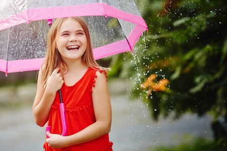 在雨中笑美丽的小女孩的肖像, 用雨伞