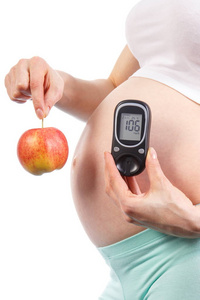 孕妇在怀孕期间举行新鲜苹果和血糖仪与结果测量血糖水平 健康营养和糖尿病的概念