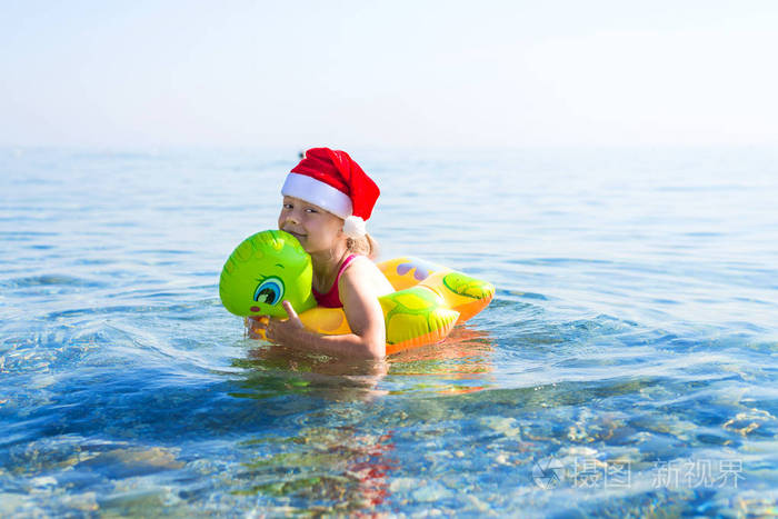 小女孩在海上游泳, 在圣诞老人帽子的充气戒指, 自由空间.