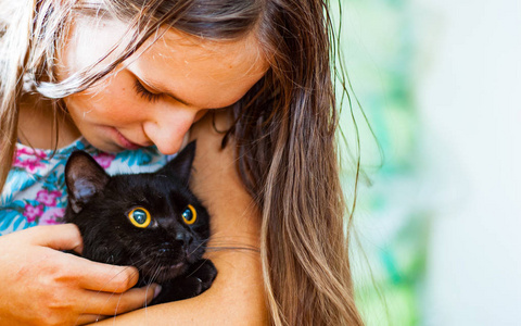 年轻的少女黑发女孩的肖像抱在她的胳膊黑猫