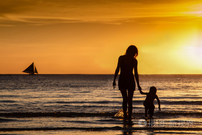母亲和儿子去破浪在日落时分