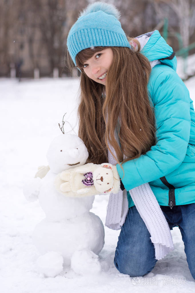 可爱的女孩在美丽的冬季公园里堆雪人可爱的孩子玩雪儿童冬季活动