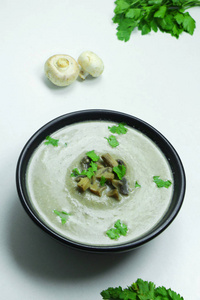 蘑菇奶油汤与香菜在一个黑色的碗白色背景