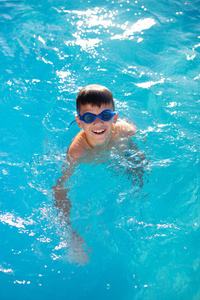 快乐的小男孩微笑在游泳池室外