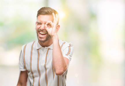 年轻英俊的人在孤立的背景下做 ok 手势用手微笑, 眼睛看通过手指与