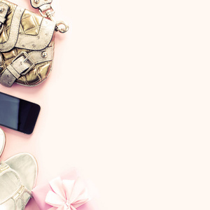 现代时尚配件年轻女子鞋手袋手机小工具礼品盒粉红色背景。顶部视图平躺