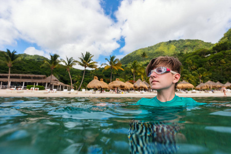 在加勒比的异国岛屿上享受暑假的少年男孩的水下照片